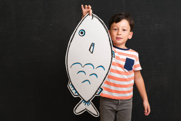 istock Cute child holding fish drawing. 1048136414