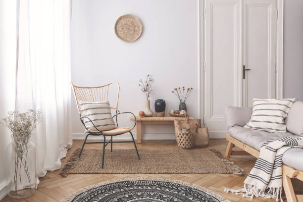 istock Armchair and sofa with patterned pillows in white flat interior with plants and round rug. Real photo 1048136548
