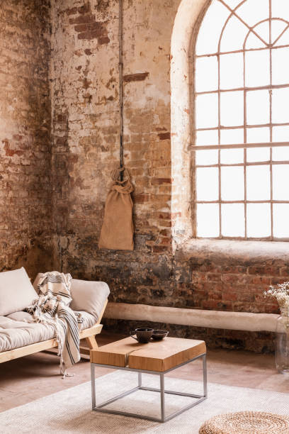 istock Blanket on grey couch in simple red brick loft interior with wooden table and window. Real photo 1048144618