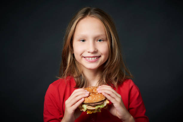 Smiling girl holding burger looking at camera