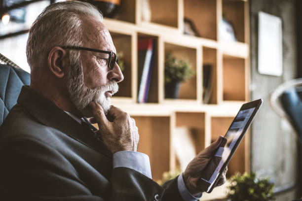 Senior businessman working on his digital tablet. Close up. stock photo