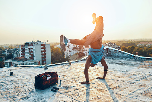 athletic and acrobatic man doing a hand stand on the roof