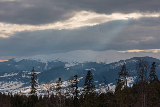 istock Evening winter mountain ridge and sun rays from cloudy sky 1048161250