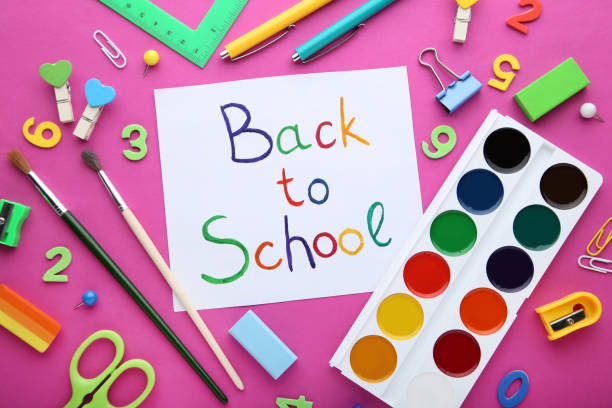 istock Inscriptions Back To School with school supplies on pink background 1048172344