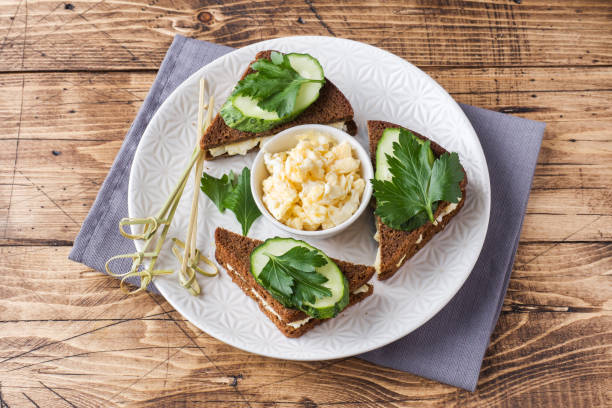 istock Sandwich with scrambled eggs, cucumbers and parsley on wooden rustic background. 1048173670