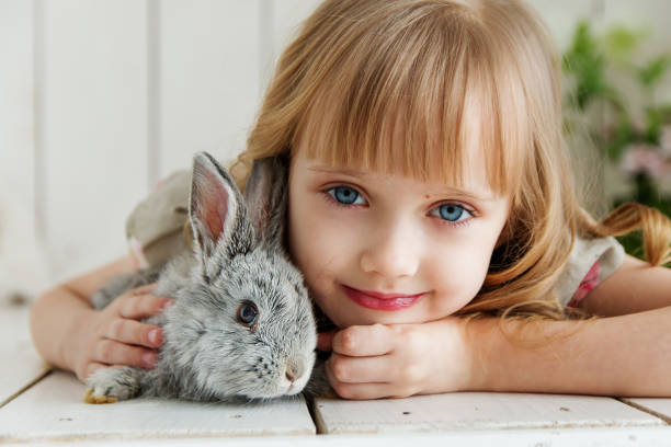 istock Young blond cute girl is holding a rabbit in her hands 1048176540