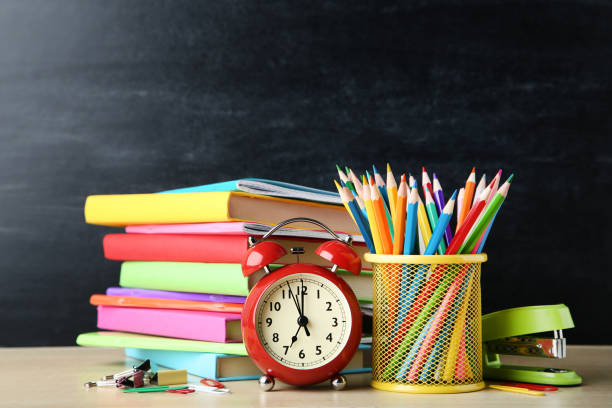 istock School books with pencils and alarm clock on blackboard background 1048184656