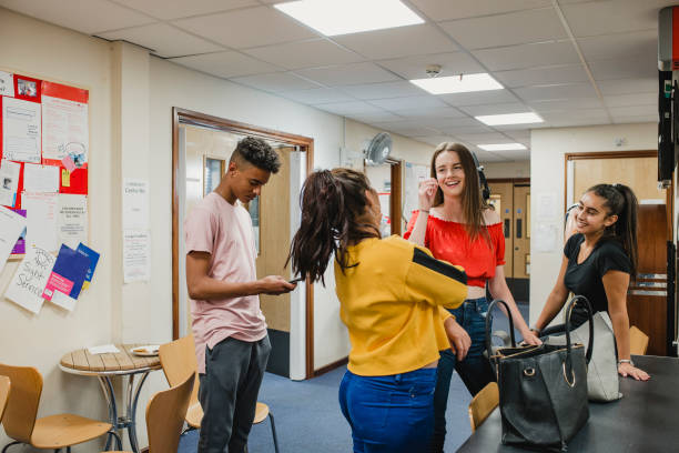 Teenagers at Youth Club Small group of female teenagers are talking in youth club. One boy is on his smart phone. teenagers only teenager multi ethnic group student stock pictures, royalty-free photos & images