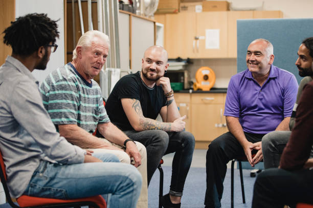 Men in a Support Group Diverse group of men are talking and laughing together in a mental health support group. community center photos stock pictures, royalty-free photos & images