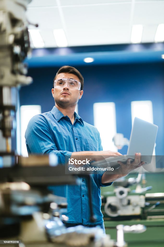 Latino engenheiro trabalhando no laptop e broca - Foto de stock de Engenheiro royalty-free