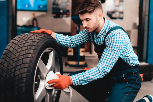 istock Young Mechanic Cleans Car Tire At Service Station. 1048208070