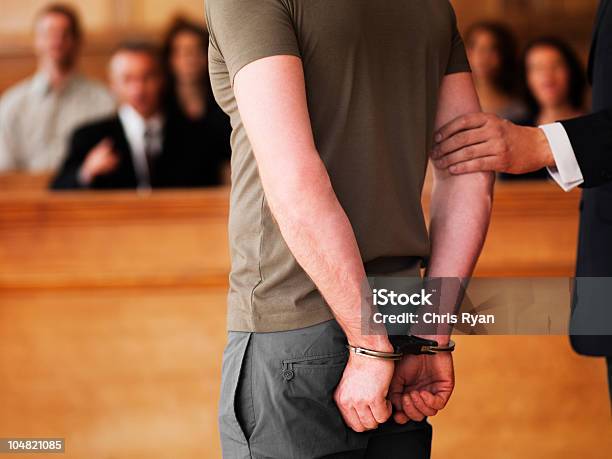 Foto de Handcuffed Homem Em Pé Na Sala De Tribunal e mais fotos de stock de Palácio de justiça - Palácio de justiça, Algema, Criminoso
