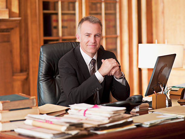avvocato sorridente seduto alla scrivania in ufficio - avvocato foto e immagini stock