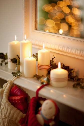Second Advent, decoration with four different candles, two are lit, green glass Christmas balls, moss and cinnamon stars on a wooden table against a light wall, copy space, selected focus
