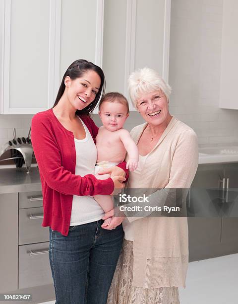 Photo libre de droit de Souriant De Grandmère Mère Tenant Bébé Dans La Cuisine banque d'images et plus d'images libres de droit de Bébé