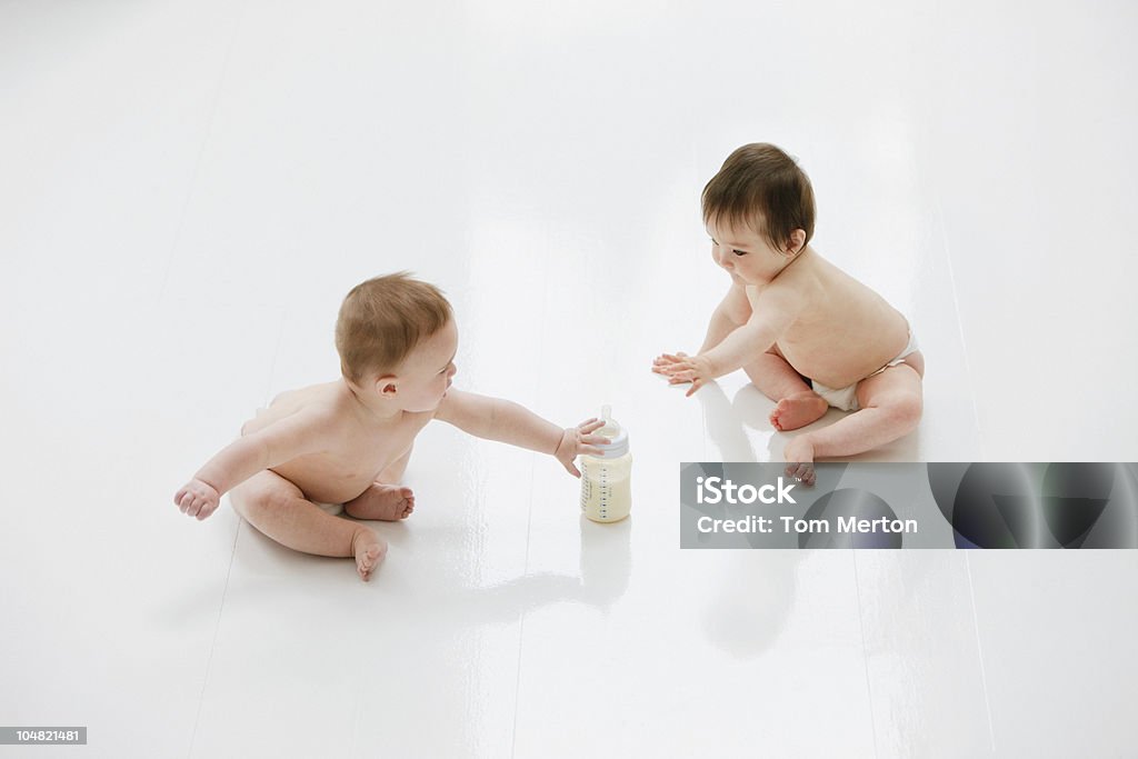 Bebés en piso con botella de leche - Foto de stock de Bebé libre de derechos