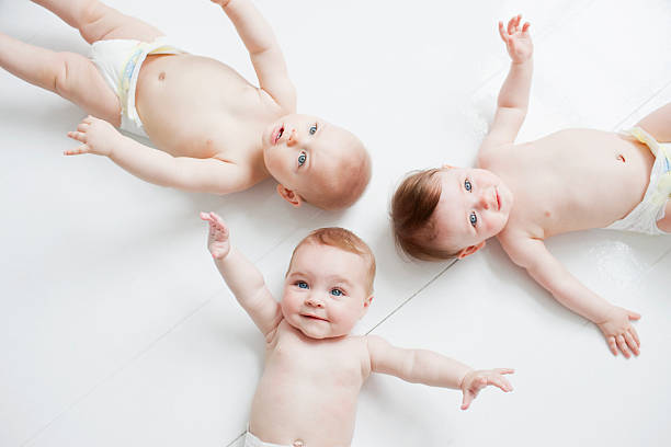 sonriente bebé que descansan en el suelo - three boys fotografías e imágenes de stock