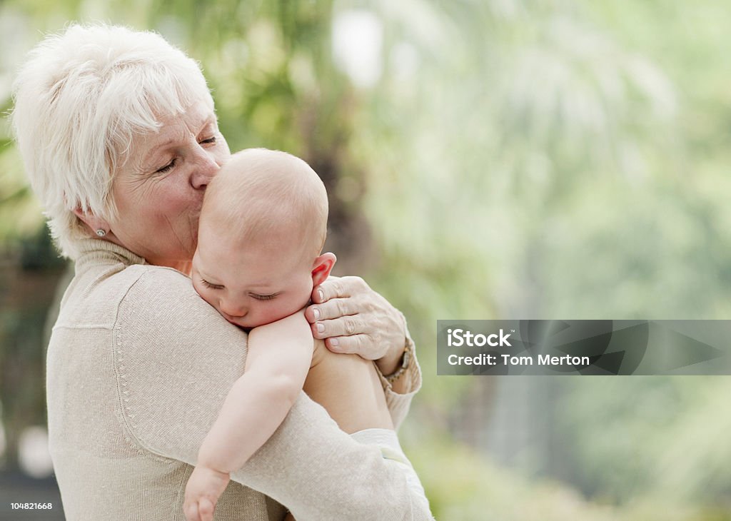 Nonna holding e baciare bambino - Foto stock royalty-free di Bebé