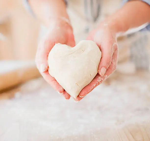 Photo of Close up of woman holding heart-shape dough