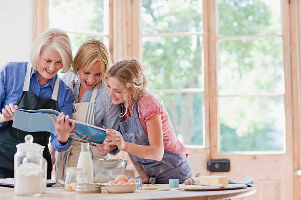 Multi-generation females looking at cookbook and baking in kitchen  recipe photos stock pictures, royalty-free photos & images