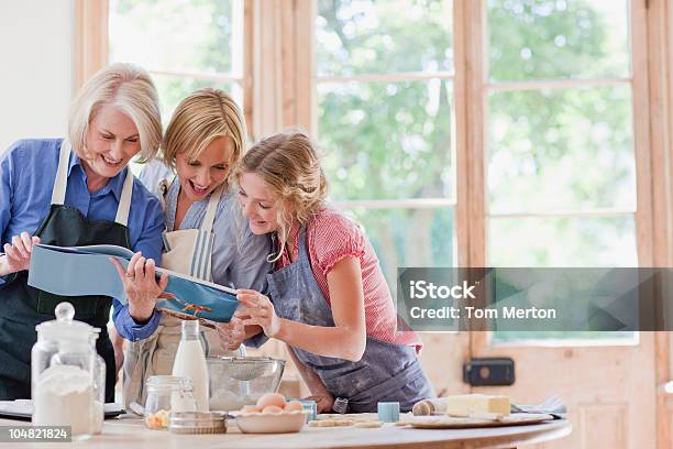 Multigeneration Females Looking At Cookbook And Baking In Kitchen Stock Photo - Download Image Now