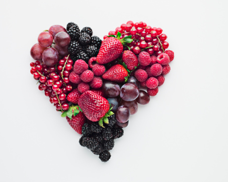 Many fresh ripe raspberries and green leaves isolated on white