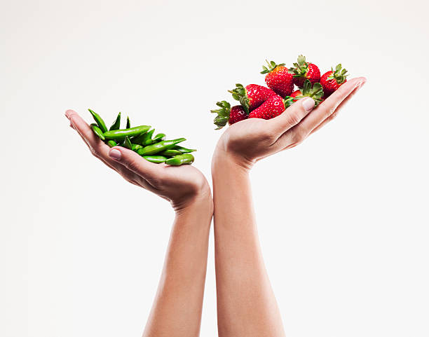 frau holding handvoll erdbeeren über handvoll pea pods - strawberry fruit single object food stock-fotos und bilder