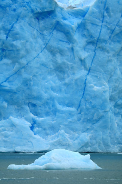 iceberg flutuando no lago argentino, com o enorme glaciar perito moreno em pano de fundo, parque nacional los glaciares, el calafate, patagônia, argentina - glacier moreno glacier iceberg argentina - fotografias e filmes do acervo