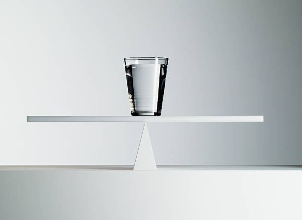 glass of water balancing on middle of seesaw - keseimbangan konsep potret stok, foto, & gambar bebas royalti