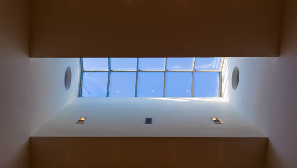 istock Looking up to the blue cloudy sky through modern square ceiling window 1048227012