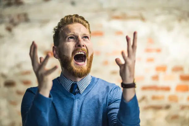 Photo of Young redhead businessman shouting from frustration.