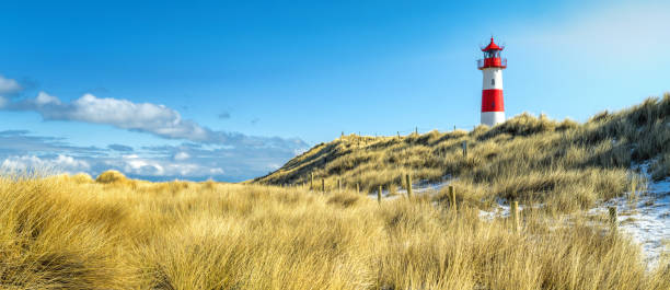 красно-белый полосатый маяк на песчаных дюнах острова сылт зимой - direction sea lighthouse landscape стоковые фото и изображения