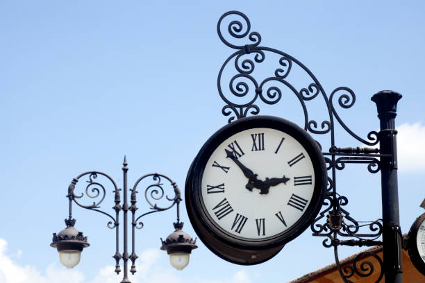istock Silhouetted vintage cast iron street light and clock, clear sky background. 1048236966