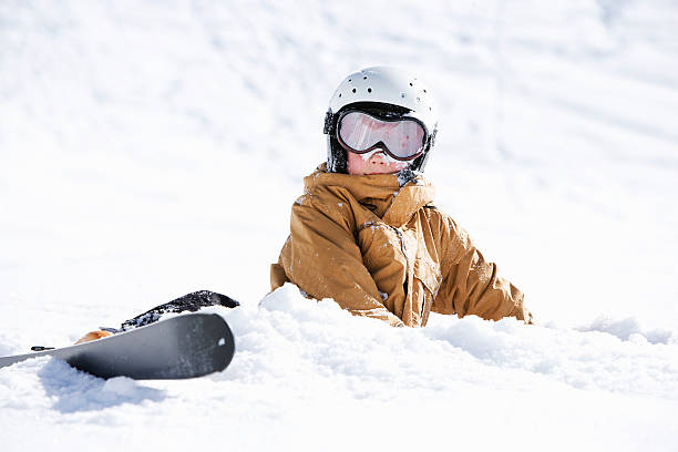 jeune garçon recouvert de neige avec des skis - sports helmet photos et images de collection