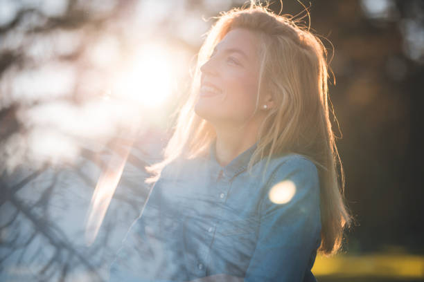 Woman enjoying in a park on a sunny summer day. She is smiling and looking into the distance.