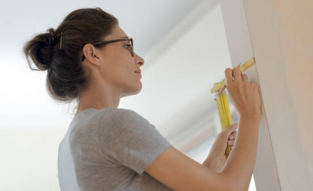 istock Woman doing a home renovation and measuring walls with a ruler 1048265156