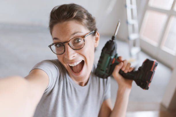 istock Cheerful woman holding a drill and taking a selfie 1048265510