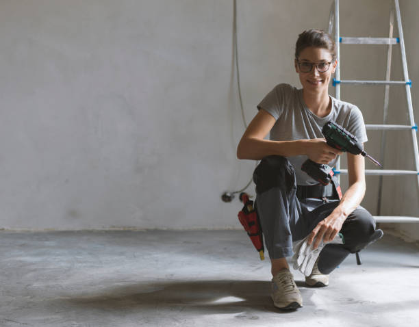 Professional repairwoman posing and holding a drill Professional repairwoman with tool belt doing a home renovation, she is posing and holding a drill woman wearing tool belt stock pictures, royalty-free photos & images