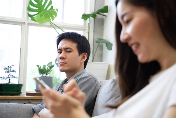 istock A Man sitting on sofa is feeling unhappy with his girlfriend while she enjoy using the phone and ignoring him. She spent too much time on the phone. Social problem in family relationship concept. 1048273920