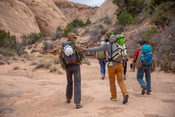 istock Three friends on a backpacking trip laugh playfully while hiking through the rocky Entrajo Trail in Moab, Utah. 1048277350