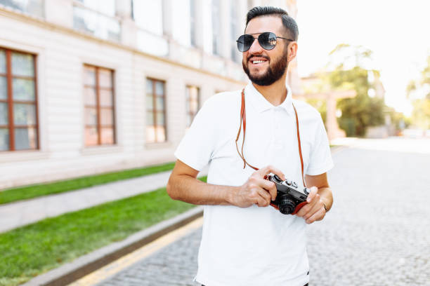 istock Stylish hipster with a beard and a camera, walking around the city with a camera 1048285686