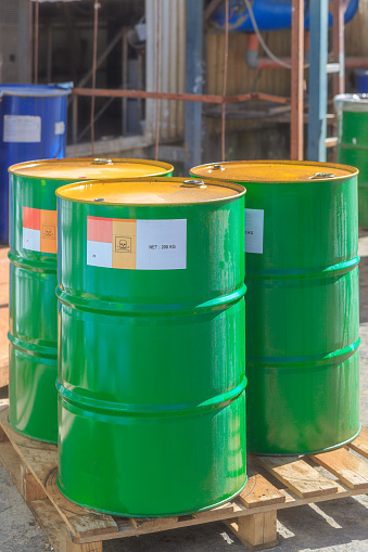 Three green barrels with label Poison standing on wooden pallets on a chemical plant