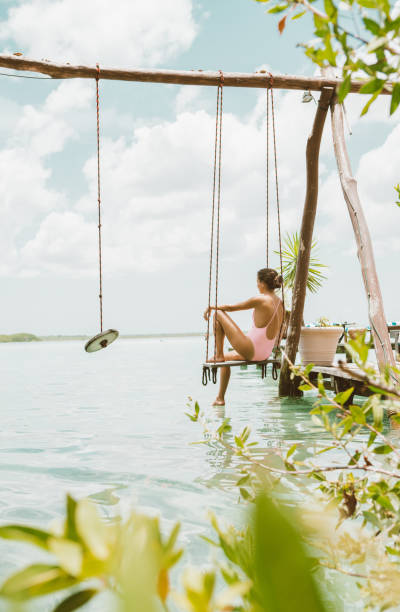 istock Woman sitting on a swing at a lagoon 1048294830