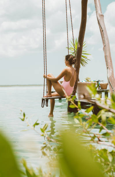 istock Woman sitting on a swing at a lagoon 1048294844