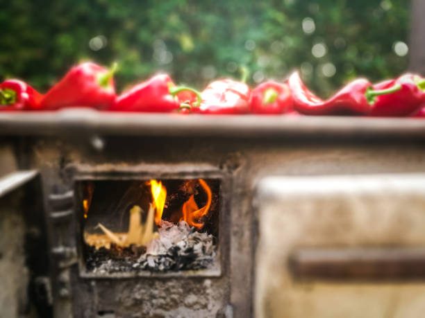 Color image depicting fresh ripe. red peppers cooking on an old-fashioned flame grill outdoors. Taken on mobile device, with room for copy space.