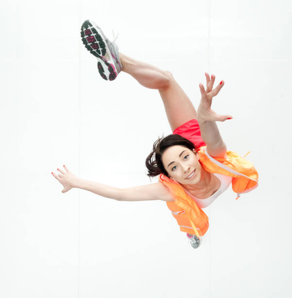 A young woman is falling as if flying through the air in front of a blue sky background.