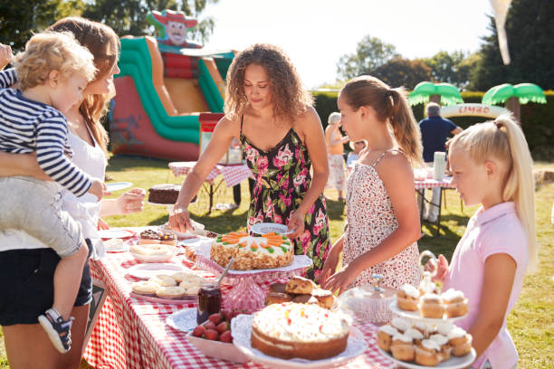 children serving on cake stall at busy summer garden fete - family child crowd british culture imagens e fotografias de stock