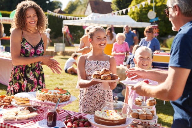 bambini che servono sulla bancarella di torte nell'affollata festa del giardino estivo - family child crowd british culture foto e immagini stock