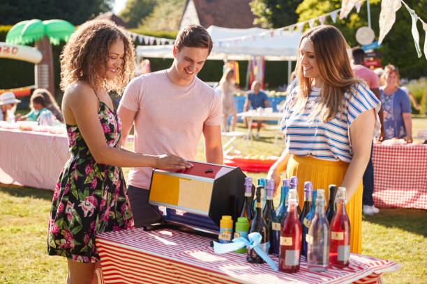 Couple At Tombola Stall At Busy Summer Garden Fete Couple At Tombola Stall At Busy Summer Garden Fete fete stock pictures, royalty-free photos & images