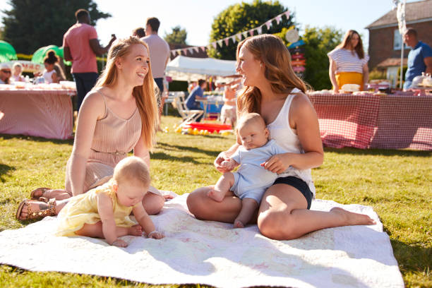 due mamme con bambini sul tappeto alla festa del giardino estivo - family child crowd british culture foto e immagini stock